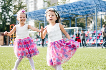 Naklejka premium two girls pull hair twins have fun in park grass 