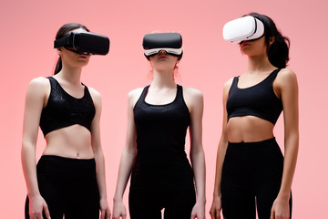 multicultural girls in sportswear and virtual reality headsets on pink