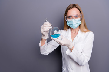 Portrait of nice attractive blonde girl qualified experienced doc holding in hands test tube analyzing biologic material inventing cure isolated over grey violet pastel color background