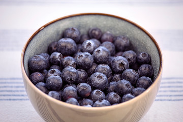 Close-up of a  bowl with blueberries on the kitchen table with tablecloth.