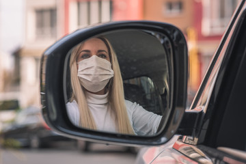 Fototapeta na wymiar girl in a medical mask. beautiful blonde photo in a car mirror