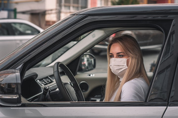 Fototapeta na wymiar girl in a medical mask. beautiful blonde driving an expensive car. coronavirus, disease, infection, quarantine, medical mask, covid-19