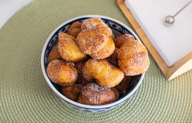 Traditional Brazilian mini fried cakes called bolinho de chuva in a bowl in a green breakfast background