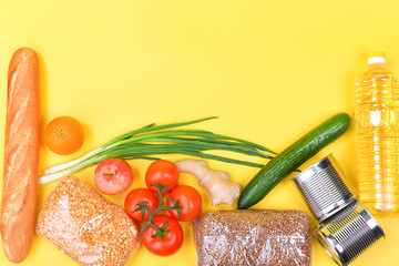 Food delivery, donation, food supply, copyspace. On a yellow background, buckwheat, pasta, sugar, peas, canned food, tomatoes, cucumber, bread, orange, apple, eggs, ginger, package.