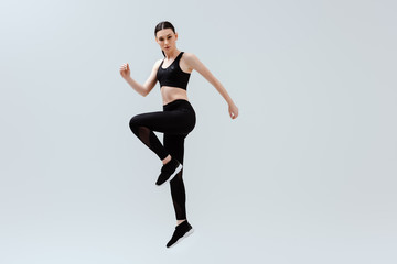 Fototapeta na wymiar sportive woman in black sportswear jumping isolated on white