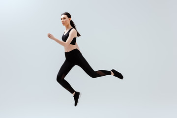 pretty woman in black sportswear jumping isolated on white