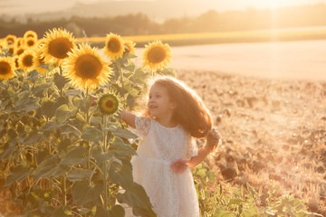 girl in a white dress in a field with sunflowers