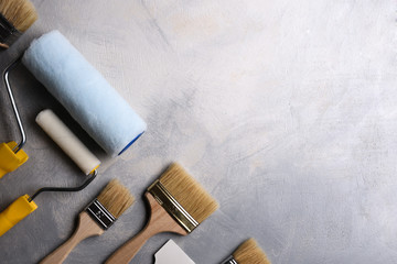 Spatulas for application of putty and brushes and rollers for painting on a gray concrete...