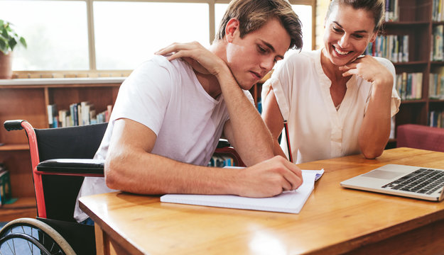 Disabled Student Studying With His Tutor