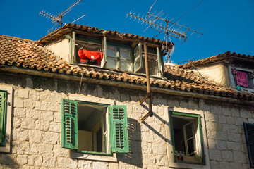 Buildings of the old city in Split, Croatia. Hot day, open shutters, red-hot roof tiles of old houses