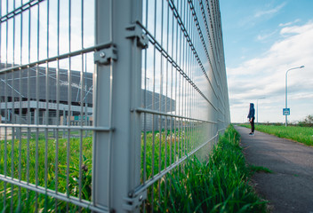 Obraz premium Sad Thoughtful teenage hipster girl standing alone in front of the metal grid