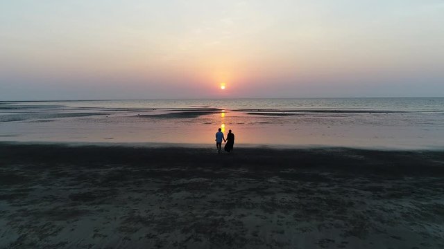 silhouette of a couple walking on the beach at sunset