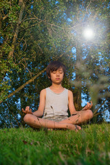 Young Asian boy practicing yoga outdoors