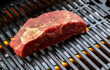 Raw fresh beef steak with spices on the grill. Ready for cooking. Close up