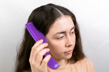 The woman is a brunette, parting her hair with a comb and showing the results of treatment for...