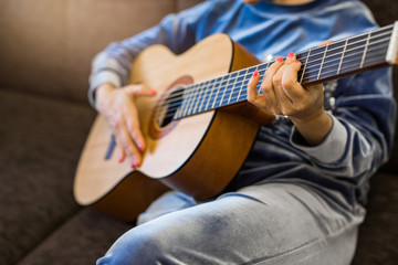 woman playing acoustic guitar at home