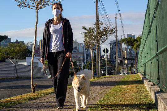 Mulher de m&aacute;scara passeando com o cachorro
