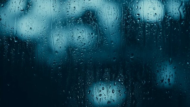 water drops on glass on night city background. abstract background. pantone color classic blue. 
