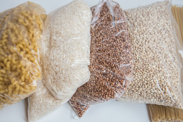 Food donations on a beige background, Cereals and pasta in transparent bags. background.