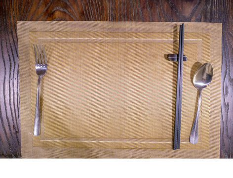 Wooden chopstick, and silver spoon and folk on table mat