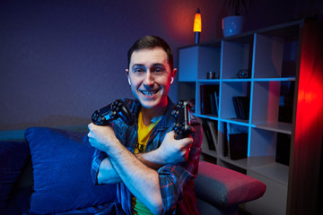 Portrait of crazy playful Gamer enjoying Playing Video Games on Playstation indoors sitting on the sofa, holding Console Gamepad in hands, Xbox fans. Resting At Home, have a great Weekend.