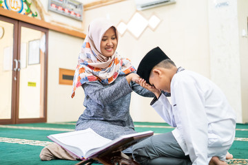 muslim kid pay respect to his teacher before studying in the mosque