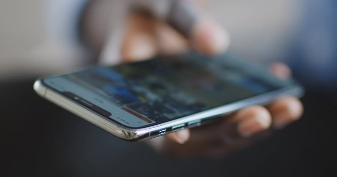 African guy scrolling social media app on cellphone, close up