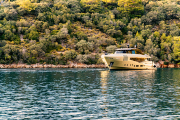 A luxury yacht anchoring in a green lagoon with calm waters reflecting environment and copy space