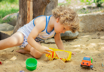 Cute  child plays in the sandbox. Little boy plays  In the yard