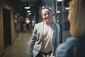 Smiling businessman talking with a coworker in an office hallway