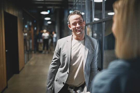 Smiling businessman talking with a coworker in an office hallway