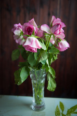 pink roses wither in a vase on a dark background