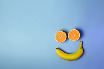 Smiley face with two oranges and a banana with copy space on a blue background