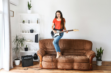 Fun at home on self-isolation. A young woman with an electric guitar in her hands dances and sings...