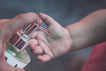 Corona virus or COVID-19 pandemic prevention, Mother put hand sanitizer to her daughter hand. wash hands with Alcohol based hand sanitizer frequently. Family hygiene concept.