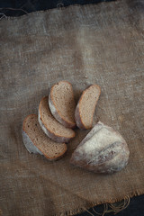 whole grain bread lies on burlap on a black wooden background
