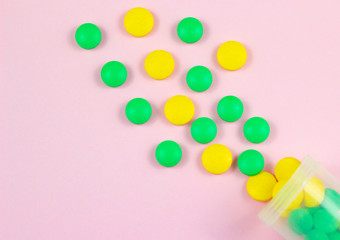 Colorful pills and tablets on a pink background.