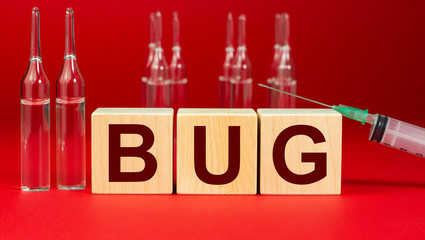 Bug, virus inscription on wooden cubes on a red background with ampoules and syringe. The concept...