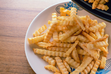 French fries on a plate, On the wood table background, Delicious and healthy because cooking in an oil-free frying pan, Selective focus.