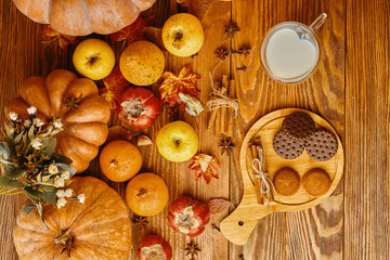 Cookies with milk on the table. Pumpkin cookies on wooden table with pumpkins on a background.