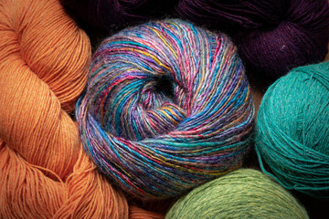Closeup of balls and skeins of yarns, richly colored, knitting and crochet handicraft background,...