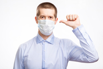 A handsome young man in a medical mask, a blue light shirt shows his finger on his head, in full-face, staring at the camera . Isolated