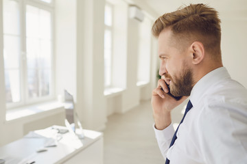 Confident adult businessman having phone conversation in office