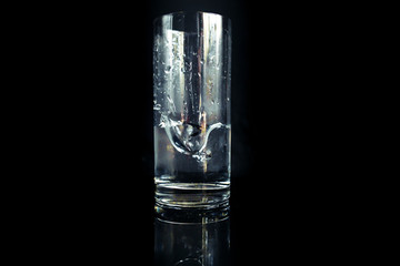 Kostka lodu wpadajaca do szklanki z wodą