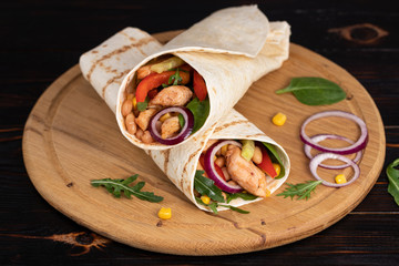Burritos wraps with chicken and vegetables on dark background. Mexican food