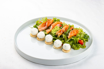 Salmon salad with cheese balls on a white plate