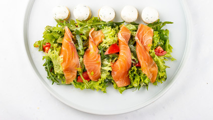 Salmon salad with cheese balls on a white plate
