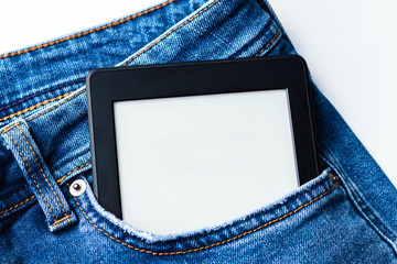 A modern black electronic book with a blank screen in the front pocket of bright blue jeans. Mockup tablet