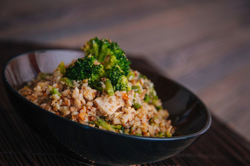 Ready buckwheat in a dark cup with vegetables. Broccoli and young beans in buckwheat. Slavic recipe
