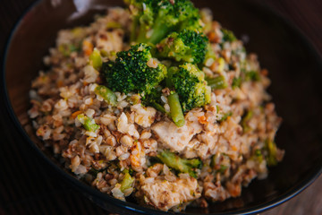 Ready buckwheat in a dark cup with vegetables. Broccoli and young beans in buckwheat. Slavic recipe